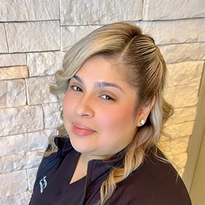 Bertha Office Assistant Smiling In Front Of Brick Wall
