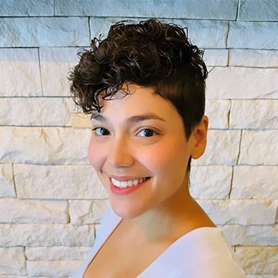 Emily Office Assistant Smiling In Front Of Brick Wall
